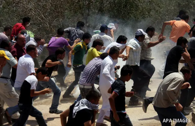 Palestinians run away from tear gas fired by Israeli soldiers, during a protest about Palestinian access to lands in the area, in the village of Kufr Qaddum near the Israeli settlement of Kdumim, in the northern West Ban...