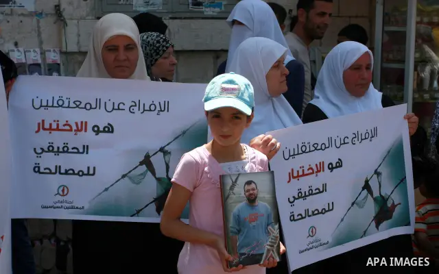 A Palestinian girl, a supporter of the Hamas movement, holds a photograph of a family member as she attends a protest demanding the release of arrested and imprisoned family members held for political reasons by the Pale...