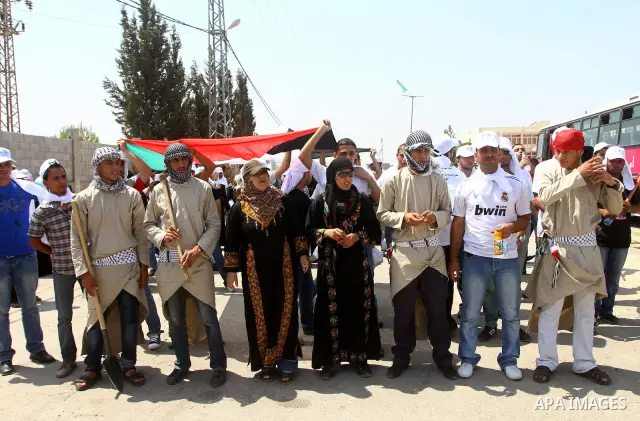 Palestinian protesters wave national flags during a demonstration on July 30, 2011 on the outskirts of Gaza City against the military zone Israel created on Palestinian land, east of the city, as a buffer between its bor...