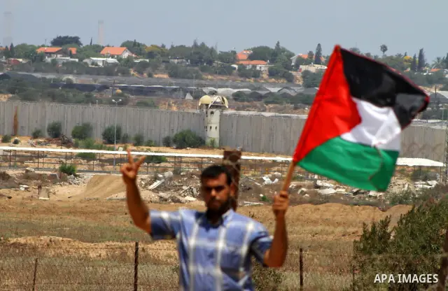Palestinian protesters wave national flags during a demonstration on July 30, 2011 on the outskirts of Gaza City against the military zone Israel created on Palestinian land, east of the city, as a buffer between its bor...