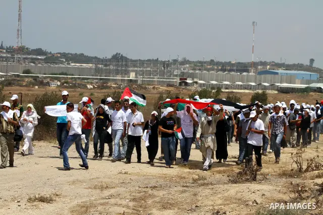 Palestinian protesters wave national flags during a demonstration on July 30, 2011 on the outskirts of Gaza City against the military zone Israel created on Palestinian land, east of the city, as a buffer between its bor...