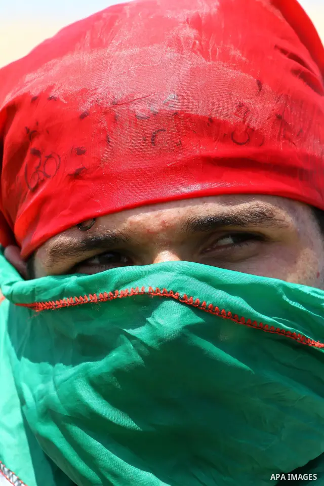 A Palestinian protester covers his face with national flag in a demonstration on July 30, 2011 on the outskirts of Gaza City against the military zone Israel created on Palestinian land, east of the city, as a buffer bet...