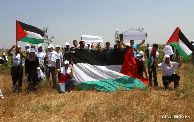 Palestinian protesters wave national flags during a demonstration on July 30, 2011 on the outskirts of Gaza City against the military zone Israel created on Palestinian land, east of the city, as a buffer between its bor...