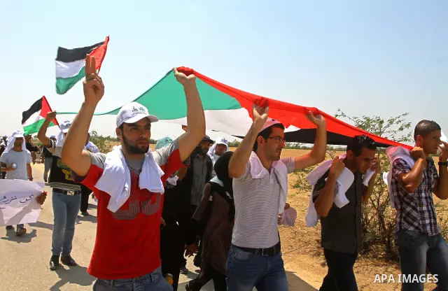 Palestinian protesters wave national flags during a demonstration on July 30, 2011 on the outskirts of Gaza City against the military zone Israel created on Palestinian land, east of the city, as a buffer between its bor...