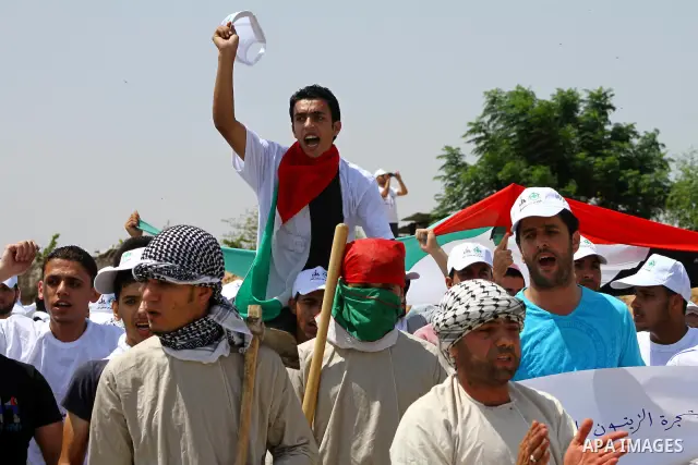 Palestinian protesters wave national flags during a demonstration on July 30, 2011 on the outskirts of Gaza City against the military zone Israel created on Palestinian land, east of the city, as a buffer between its bor...