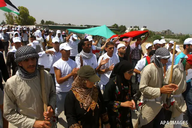 Palestinian protesters wave national flags during a demonstration on July 30, 2011 on the outskirts of Gaza City against the military zone Israel created on Palestinian land, east of the city, as a buffer between its bor...