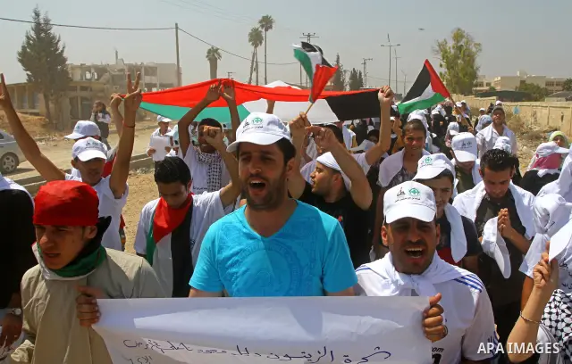 Palestinian protesters wave national flags during a demonstration on July 30, 2011 on the outskirts of Gaza City against the military zone Israel created on Palestinian land, east of the city, as a buffer between its bor...