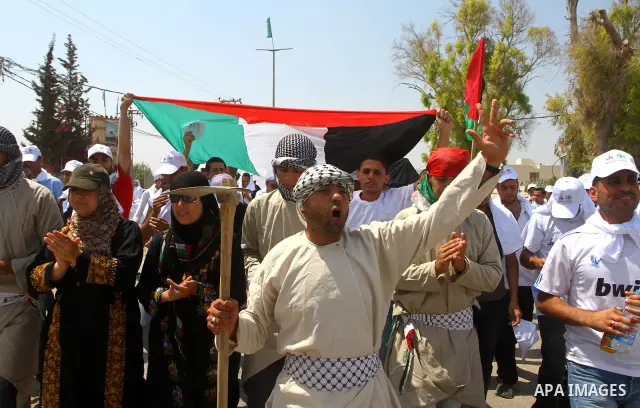Palestinian protesters wave national flags during a demonstration on July 30, 2011 on the outskirts of Gaza City against the military zone Israel created on Palestinian land, east of the city, as a buffer between its bor...