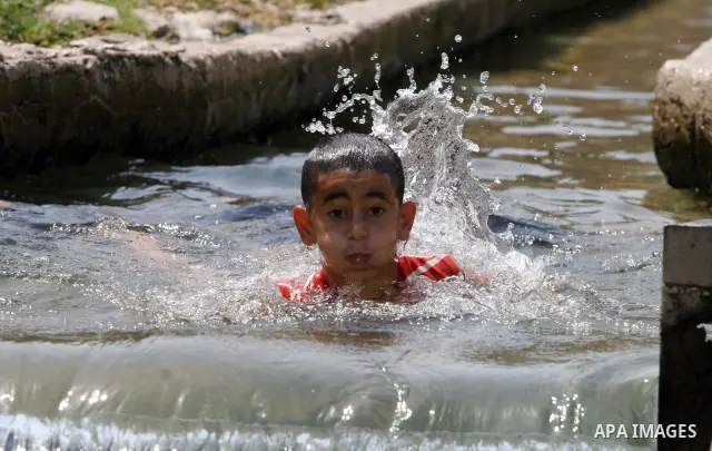 Palestinians immerse themselves in a running stream of channelled irrigation water as they cool off in the biblical city of Jericho where the temperatures soared to 47 degrees Celsius, on July 30, 2011. Photo by Issam Ri...