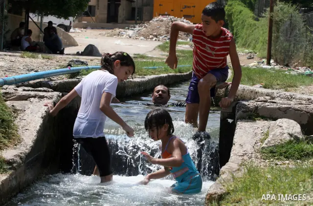 Palestinians immerse themselves in a running stream of channelled irrigation water as they cool off in the biblical city of Jericho where the temperatures soared to 47 degrees Celsius, on July 30, 2011. Photo by Issam Ri...