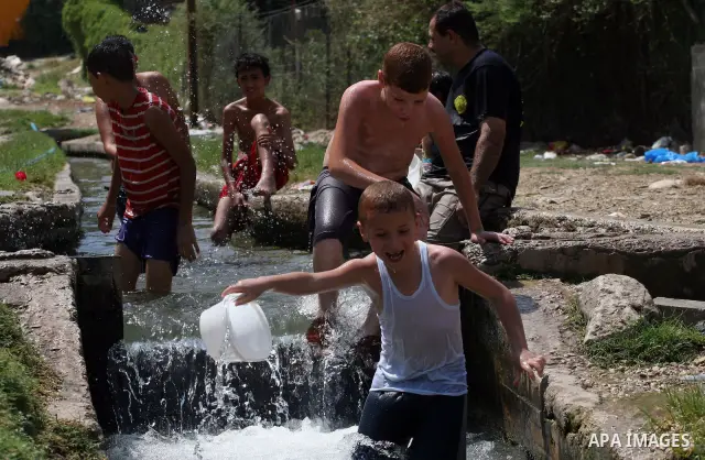 Palestinians immerse themselves in a running stream of channelled irrigation water as they cool off in the biblical city of Jericho where the temperatures soared to 47 degrees Celsius, on July 30, 2011. Photo by Issam Ri...