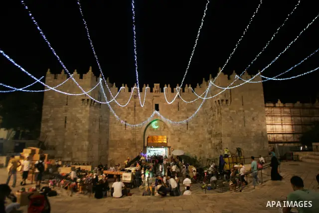 Palestinians stand under decorations for the upcoming holy month of Ramadan near Damascus Gate in Jerusalem's Old City July 31, 2011. Muslims around the world abstain from eating, drinking and conducting sexual relations...