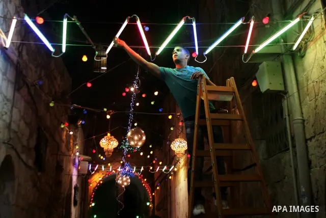 A Palestinian man hangs decorations for the upcoming holy month of Ramadan outside his home in Jerusalem's Old City July 31, 2011. Muslims around the world abstain from eating, drinking and conducting sexual relations fr...