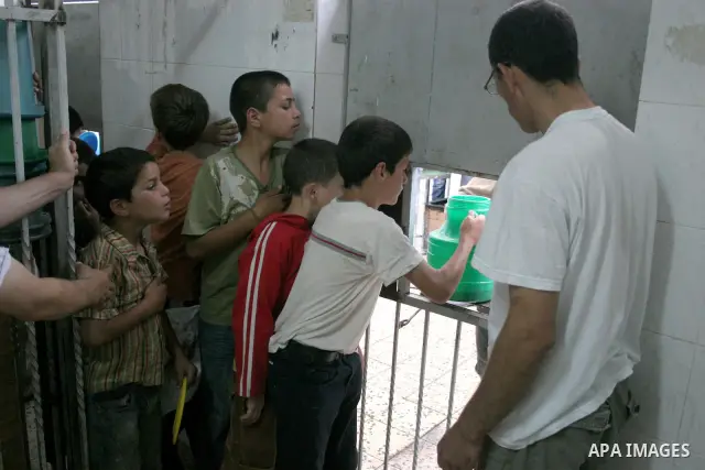 Palestinian families carry containers as they wait to receive free food for 'Iftar', the meal that breaks the daily fast during Ramadan, at an Islamic Council charity in the centre of the West Bank city of Hebron on Augu...