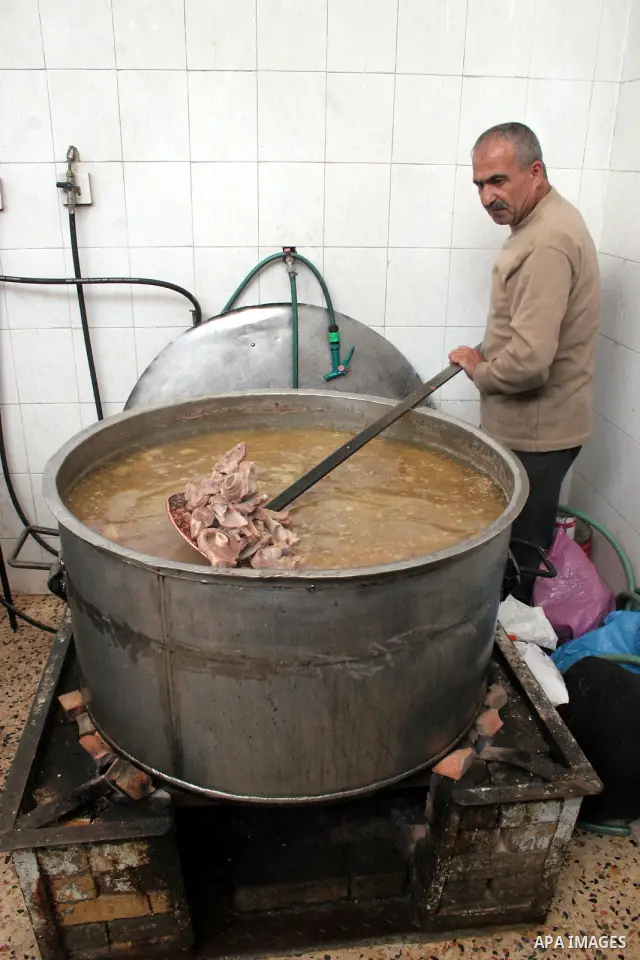 Palestinian families carry containers as they wait to receive free food for 'Iftar', the meal that breaks the daily fast during Ramadan, at an Islamic Council charity in the centre of the West Bank city of Hebron on Augu...