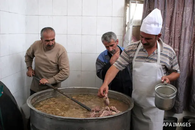Palestinian families carry containers as they wait to receive free food for 'Iftar', the meal that breaks the daily fast during Ramadan, at an Islamic Council charity in the centre of the West Bank city of Hebron on Augu...