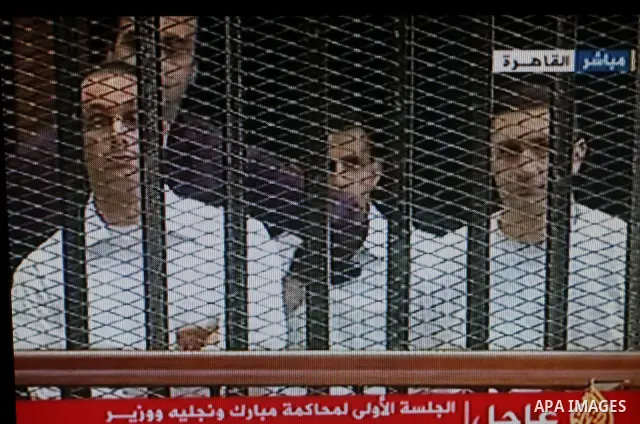 This video image taken from Egyptian State Television shows the sons of Hosni Mubarak stand inside the cage of mesh and iron bars in a Cairo courtroom Wednesday Aug. 3, 2011 as his historic trial began on charges of corr...