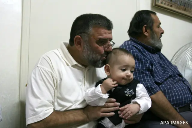 A Palestinian commander of the Hamas Islamist movement, Sheikh Hassan Yusef, 56, hugs his son in his home in the West Bank city of Ramallah after he was released from an Israeli jails, on Aug. 4, 2011. as Israel free 770...