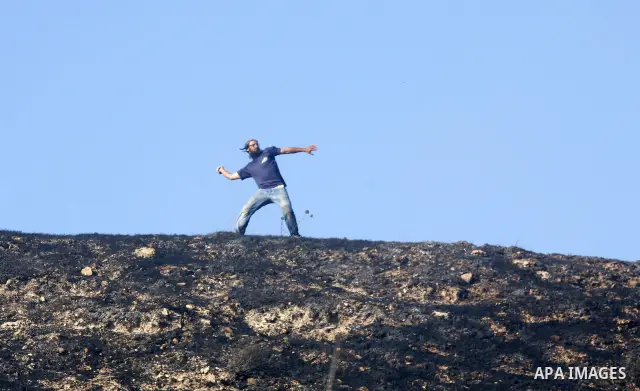 Israeli settlers hurl rocks at Palestinians, not seen, on the outskirts of Burin village, near the Jewish settlement burning fields on Palestinian land close to the village of Burin, near the West Bank town of Nablus, on...