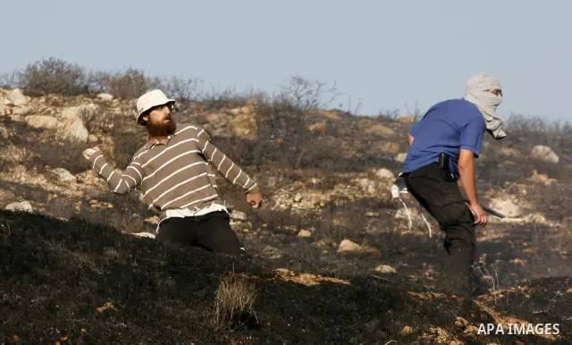 Israeli settlers hurl rocks at Palestinians, not seen, on the outskirts of Burin village, near the Jewish settlement burning fields on Palestinian land close to the village of Burin, near the West Bank town of Nablus, on...