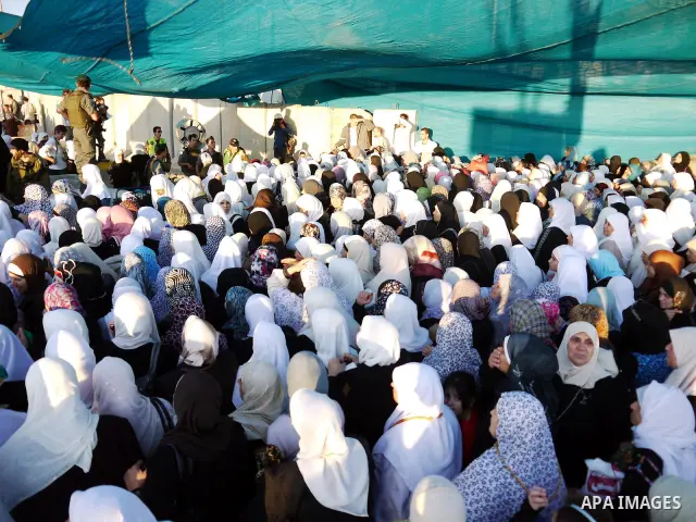 Palestinian women wait to cross the Qalandia checkpoint on their way to pray at the Al Aqsa Mosque on the first Friday of the Muslim holy month of Ramadan, at the Qalandia checkpoint between the West Bank city of Ramalla...