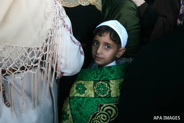 A Palestinian boy with his mother wait to cross the Qalandia checkpoint on their way to pray at the Al Aqsa Mosque on the first Friday of the Muslim holy month of Ramadan, at the Qalandia checkpoint between the West Bank...