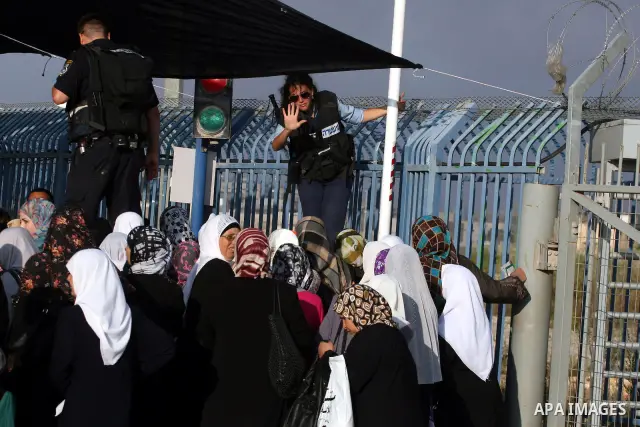 Palestinian women wait to cross the Qalandia checkpoint on their way to pray at the Al Aqsa Mosque on the first Friday of the Muslim holy month of Ramadan, at the Qalandia checkpoint between the West Bank city of Ramalla...