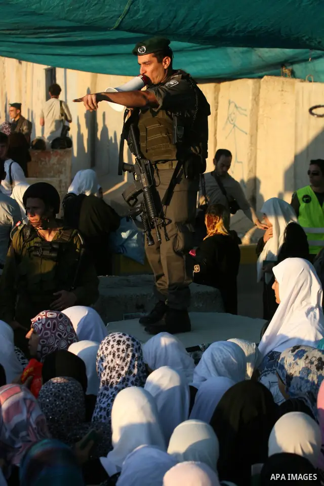 Palestinian women wait to cross the Qalandia checkpoint on their way to pray at the Al Aqsa Mosque on the first Friday of the Muslim holy month of Ramadan, at the Qalandia checkpoint between the West Bank city of Ramalla...