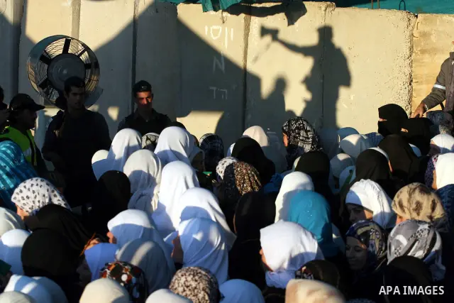 Palestinian women wait to cross the Qalandia checkpoint on their way to pray at the Al Aqsa Mosque on the first Friday of the Muslim holy month of Ramadan, at the Qalandia checkpoint between the West Bank city of Ramalla...