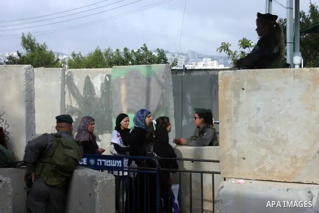 Israeli border policemen check the IDs of the Palestinian female worshippers as they waiting in line to pass at Qalandia checkpoint that leads from the West Bank town of Ramallah to Jerusalem on Aug. 5, 2011, in order to...