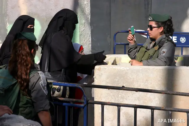 Israeli border policemen check the IDs of the Palestinian female worshippers as they waiting in line to pass at Qalandia checkpoint that leads from the West Bank town of Ramallah to Jerusalem on Aug. 5, 2011, in order to...