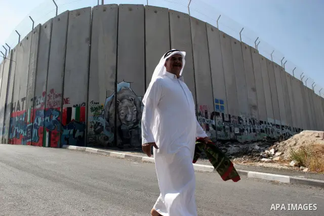 A Palestinian man walks past a mural painted on a section of the controversial Israeli barrier near an Israeli checkpoint to Jerusalem in the West Bank city of Bethlehem during the first Friday of the holy month of Ramad...