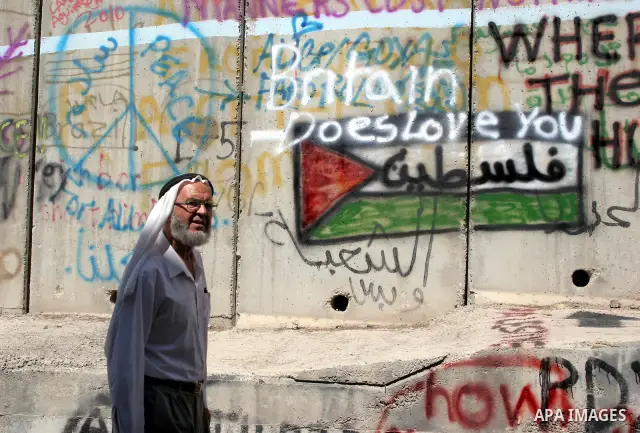 A Palestinian man walks past a mural painted on a section of the controversial Israeli barrier near an Israeli checkpoint to Jerusalem in the West Bank city of Bethlehem during the first Friday of the holy month of Ramad...