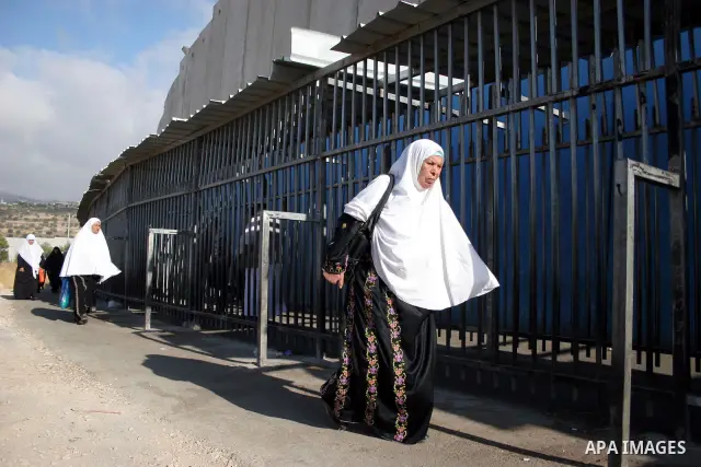 Palestinian women walk in line to cross from the Qalandia checkpoint that leads from the West Bank town of Ramallah to Jerusalem on 05 August 2011, in order to attend the Friday prayers in the holy Muslim month of Ramada...