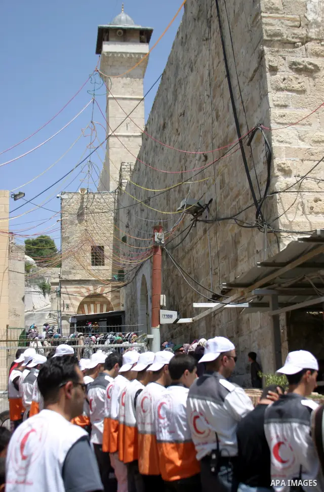 Israeli soldiers stand guard as Palestinian men perform the first Friday prayer of the holy Muslim month of Ramadan in front of the closed Ibrahimi mosque in the West Bank city of Hebron, Aug. 5, 2011. Photo by Najeh Has...