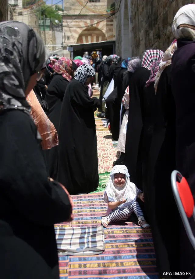 Israeli soldiers (not seen) stand guard as the Palestinian women perform the first Friday prayer of the holy Muslim month of Ramadan in front of the closed Ibrahimi mosque in the West Bank city of Hebron, August 05 2011....