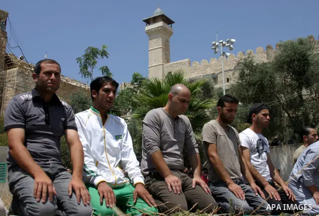 Palestinian Muslims pray at the entrance to the Ibrahimi Mosque, in the West Bank city of Hebron, on 05 August 2011. Muslims throughout the world are marking the month of Ramadan, during which they refrain from eating, d...