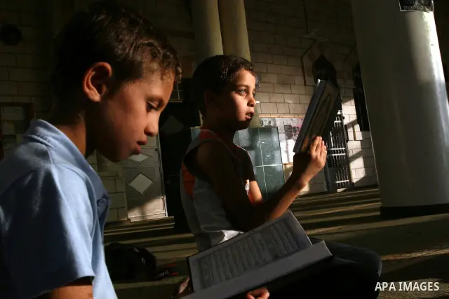 Palestinian boys read the holy Koran at the Big Mosque in the West Bank town of Ramallah, during the Muslim holy fasting month of Ramadan, on Aug. 6, 2011. Muslims throughout the world are celebrating the holy fasting mo...