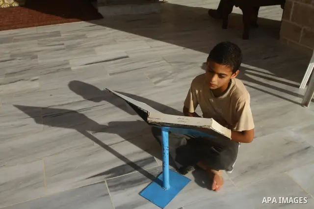 A Palestinian boy reads the holy Koran at al-Omari Mosque in Gaza city, during the Muslim holy fasting month of Ramadan, on Aug. 6, 2011. Muslims throughout the world are celebrating the holy fasting month of Ramadan, th...