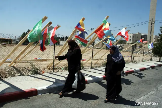 Palestinian women walk past flags of countries that have recognised the Palestinian state in the West Bank city of Ramallah on Aug. 7, 2011. The flags were raised by local youth groups ahead of the U.N. General Assembly...