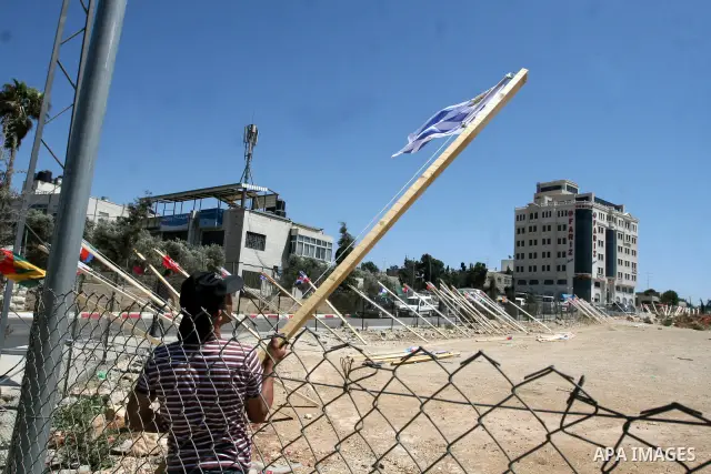 A Palestinian woman stands near flags of countries that have recognised the Palestinian state in the West Bank city of Ramallah on Aug. 7, 2011. The flags were raised by local youth groups ahead of the U.N. General Assem...