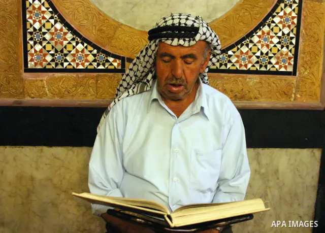 A Palestinian man reads the holy Koran at the Ibrahimi Mosque in the West Bank city of Hebron,on Aug. 8, 2011. Muslims around the world are observing the fasting month of Ramadan during which they refrain from eating, dr...