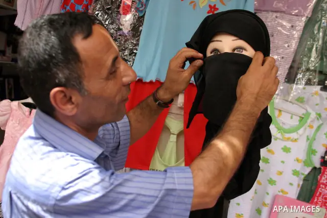 A Palestinian vendor sells clothes at his shop in the West Bank city of Hebron on Aug. 8, 2011. Muslims around the world abstain from eating, drinking and conducting sexual relations from sunrise to sunset during Ramadan...