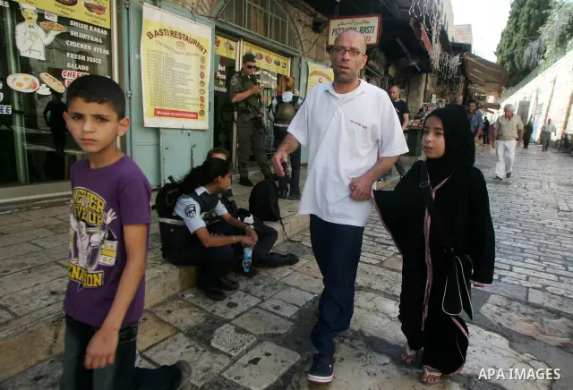 Palestinians are seen silhouetted at the entrance of the brightly lit Al-Aqsa mosque compound, in the old city of Jerusalem, during the holy month of Ramadan. 8 August 2011. Photo by Mahfouz Abu Turk