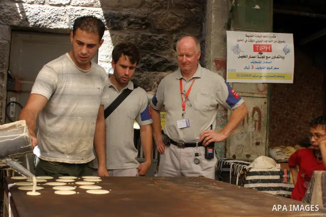 An international observer assists Palestinian shop owners in the old city of Hebron while preparing Ramadan sweets, in the divided West Bank city of Hebron on Aug. 9 2011. According to media report, temporary Internation...