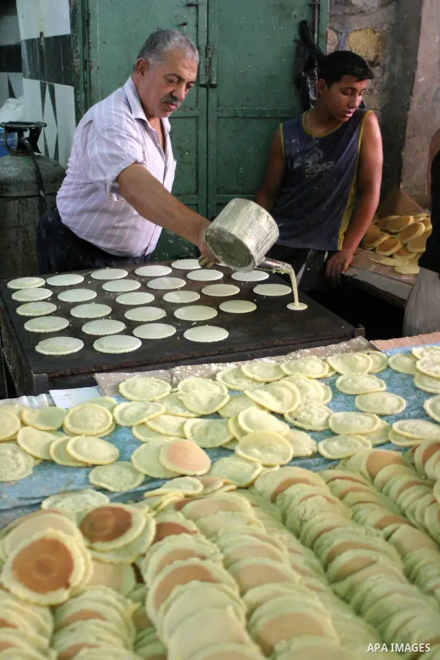 Palestinian vendors prepare qatayef, a pancake-like shell which is filled with nuts or sweet cheese, fried in oil or baked then dipped in sugar syrup, a popular sweet during Ramadan, in a shop in the West Bank city of He...