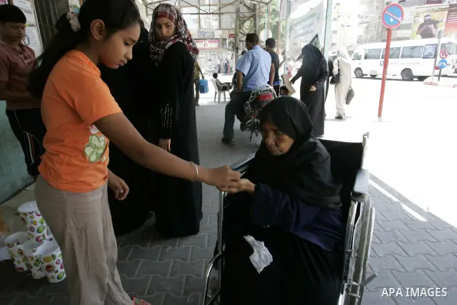 A Palestinian girl gives the charity "Zakat" to a poor woman sitting on her wheelchair at a market in the holiest month of Ramadan in Rafah, southern Gaza Strip on Aug. 11, 2011. Muslims throughout the world are marking...