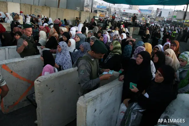 Palestinian women wait in line to pass through the Kalandia checkpoint from the West Bank town of Ramallah to Jerusalem, 12 August 2011, to attend the second Friday prayers in the Muslim holy month of Ramadan at al-Aqsa...
