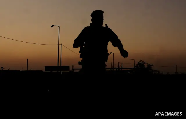 An Israeli soldier stands guard at Israel's Qalandiya checkpoint as Palestinians wait to cross into Jerusalem from the checkpoint outside the West Bank city of Ramallah, during the second Friday of the holy month of Rama...