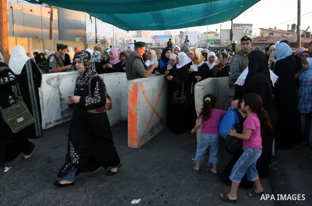 Palestinian women wait in line to pass through the Kalandia checkpoint from the West Bank town of Ramallah to Jerusalem, 12 August 2011, to attend the second Friday prayers in the Muslim holy month of Ramadan at al-Aqsa...